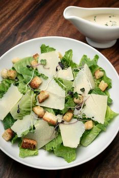 caesar salad with parmesan cheese and croutons on wood table