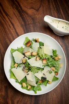 caesar salad with parmesan cheese and croutons on wood table