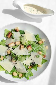 caesar salad with parmesan cheese and croutons on white table