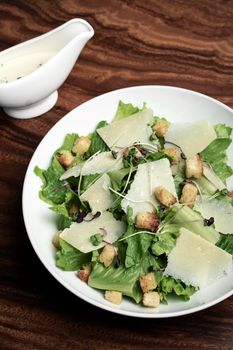 caesar salad with parmesan cheese and croutons on wood table