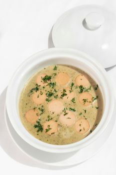 German traditional KARTOFFELSUPPE potato and sausage soup on white tabel background