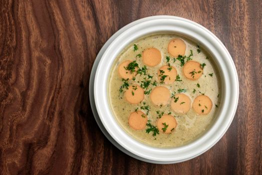 German traditional KARTOFFELSUPPE potato and sausage soup on wood table background