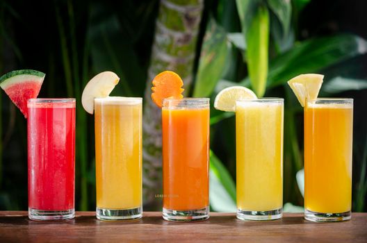 mixed fresh organic fruit juice glasses selection on sunny garden table