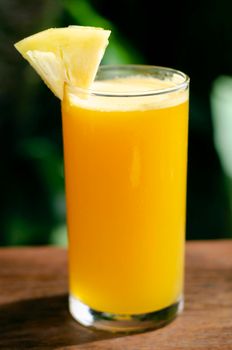 glass of fresh organic pineapple juice on table outdoors on table in sunny garden outdoors