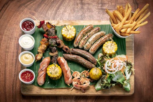 organic mixed grill barbecue meat platter rustic set meal with sausages, skewers, side dishes and sauces