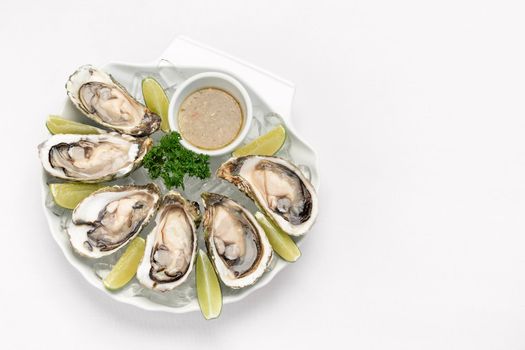 Six fresh oysters with lime wedges and citrus vinaigrette sauce