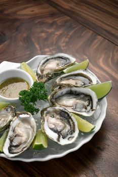 Six fresh oysters with lime wedges and citrus vinaigrette sauce