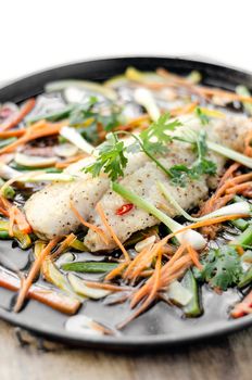 chinese cantonese style steamed spicy fish fillet with vegetables on hot plate