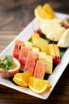 mixed fresh cut organic fruit salad platter outdoors on wood table