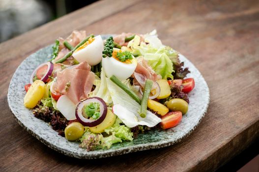 nicoise style healthy organic rustic salad with egg and ham outdoors