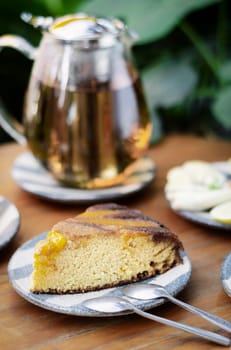 organic mango cake and herbal tea set on rustic cafe table outdoors