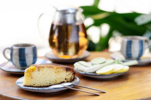organic mango cake and herbal tea set on rustic cafe table outdoors