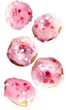 Valentine's Day. Flying donuts. Sweet pink donuts with heart sprinkles flying isolated on white background