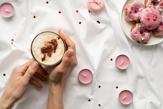 valentines day concept. Small donuts on white bed with cup of coffe and pink candles