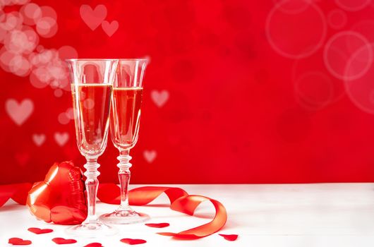 Valentines Day. Two champagne glasses, gift boxes and candles on beautiful bokeh background with copy space