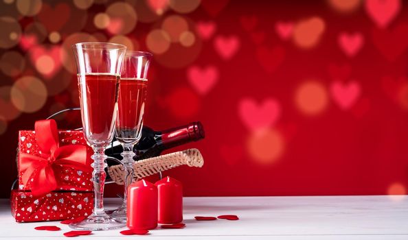 Valentines Day. Two champagne glasses, gift boxes and candles on beautiful bokeh background with copy space