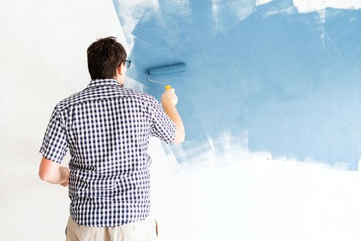 Home repair and improvement. Man coloring wall blue with a roller