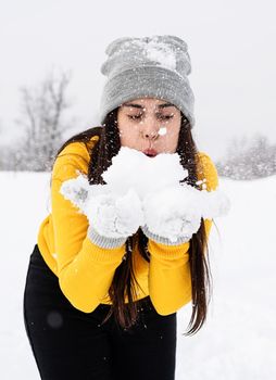 Outdoor concept. Young brunette woman playing with snow in park
