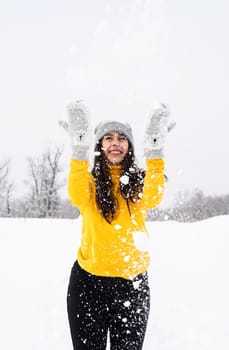 Outdoor concept. Young brunette woman playing with snow in park