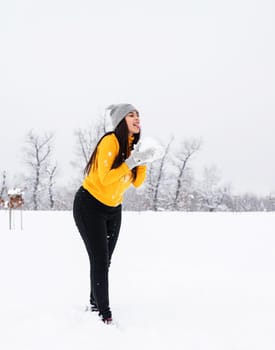 Outdoor concept. Young brunette woman playing with snow in park