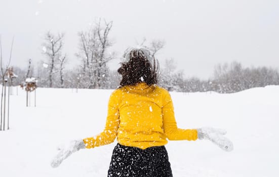 Winter season. Young brunette woman playing with snow in park