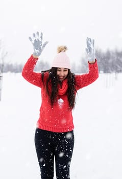 Winter season. Young brunette woman in red sweater playing with snow in park