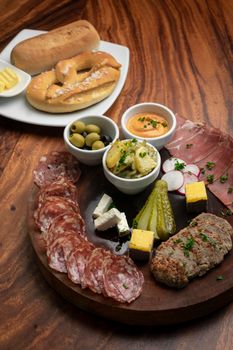 german cold cuts tapas snack platter with meats and bread on wood table background