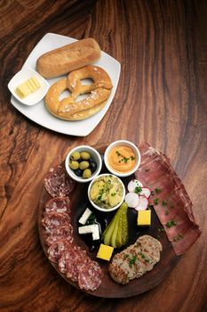 german cold cuts tapas snack platter with meats and bread on wood table background