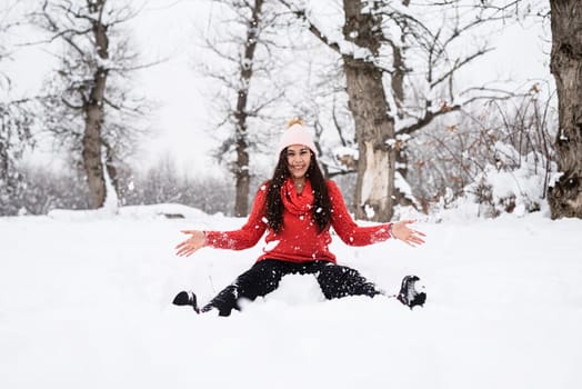 Winter season. Young brunette woman in red sweater playing with snow in park