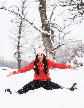 Winter season. Young brunette woman in red sweater playing with snow in park