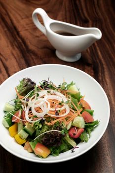 fresh organic mixed vegetable vegan Garden Salad with Vinaigrette sauce on wooden table