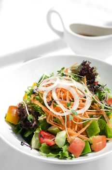 fresh organic mixed vegetable vegan Garden Salad with Vinaigrette sauce on white table