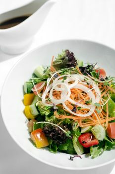 fresh organic mixed vegetable vegan Garden Salad with Vinaigrette sauce on white table