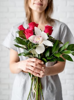 woman hands holding orchid and roses bouquet celebrating holiday