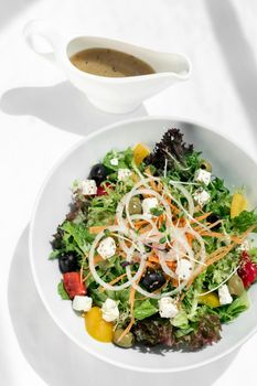 greek salad with feta cheese and olives with citrus vinaigrette on white table