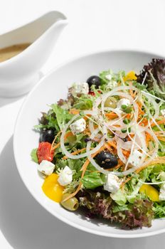 greek salad with feta cheese and olives with citrus vinaigrette on white table