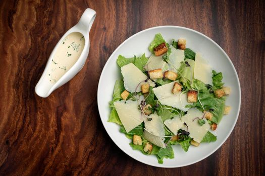 caesar salad with parmesan cheese and croutons on wood table