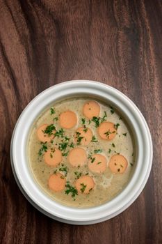 German traditional KARTOFFELSUPPE potato and sausage soup on wood table background