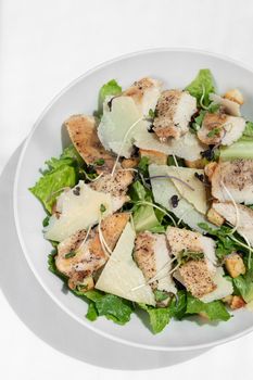 organic chicken caesar salad with parmesan cheese and croutons on white table background