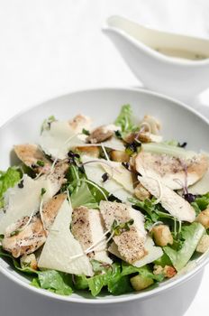 organic chicken caesar salad with parmesan cheese and croutons on white table background