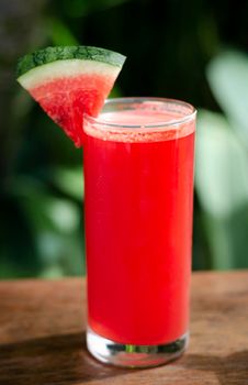 glass of fresh organic watermelon juice on garden table outdoors on sunny day