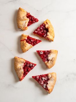 Perfect slices of raspberry galette. Delicious rustic homemade tart with frozen or fresh raspberries, white marble background. Beautiful galette pieces with raspberries,copy space. Top view, flat lay