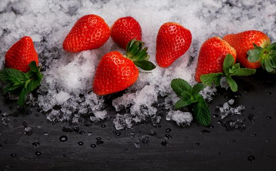 Strawberries, mint and iceon the black background.