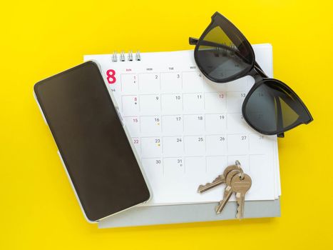 Dark glasses, keys, cell phone, and calendar prepare for departure.