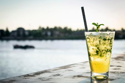 orange mojito summer cocktail drink on outdoor riverside bar tabe