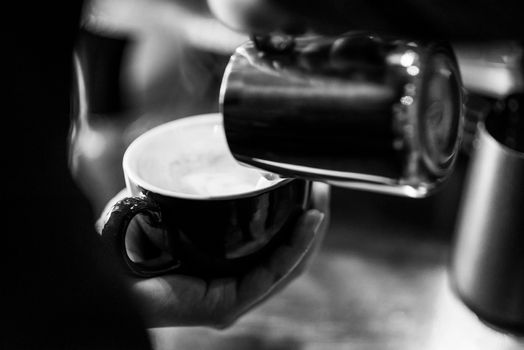 making espresso coffee BW black and white close up detail with modern cafe machine and glasses