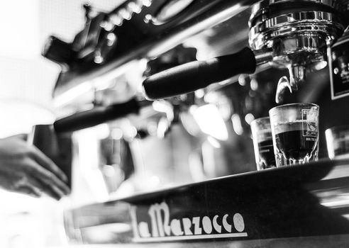 making espresso coffee BW black and white close up detail with modern cafe machine and glasses