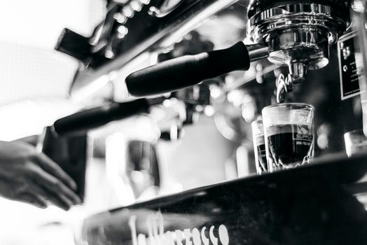 making espresso coffee BW black and white close up detail with modern cafe machine and glasses