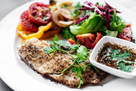 tilapia fish fillet with mixed salad grilled vegetables and herb Vinaigrette sauce