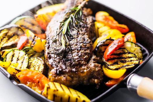 greek organic lamb steak with grilled vegetables and herbs in sizzling skillet